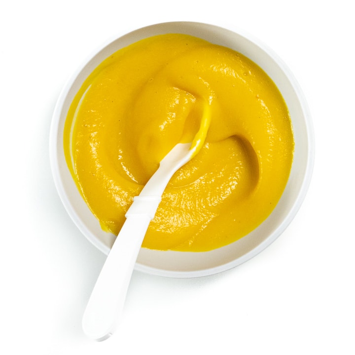 Small gray bowl filled with pumpkin puree baby food.
