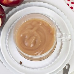 Image of a clear bowl filled with baby food puree with produce surrounding it and a spoon in front with a bite for baby.