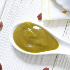 White spoon filled with creamy homemade baby food puree.