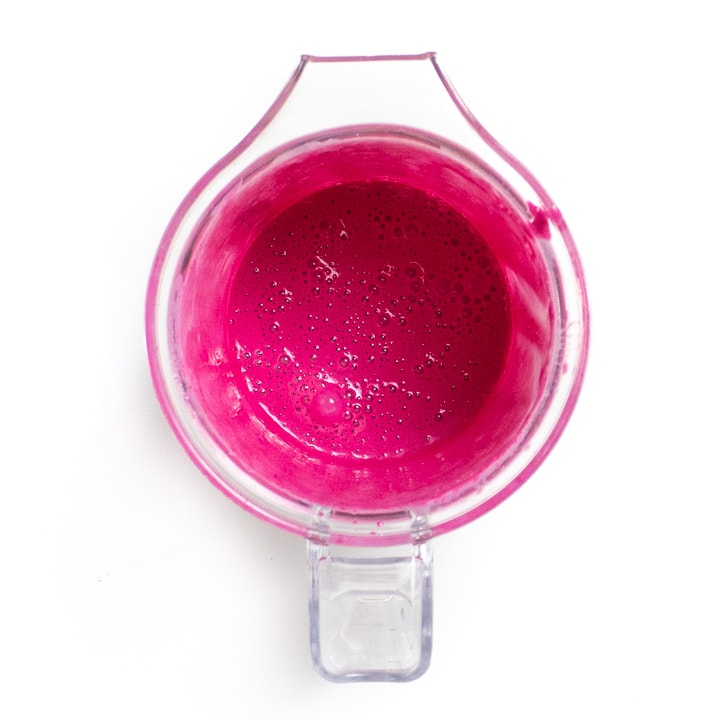 Small blender of wet ingredients dyed pink because of the beet.