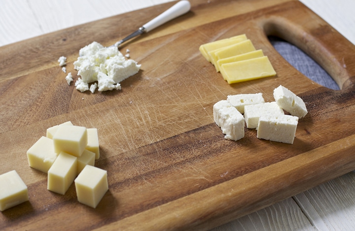 Cutting board with a selection of cheeses for baby on it.