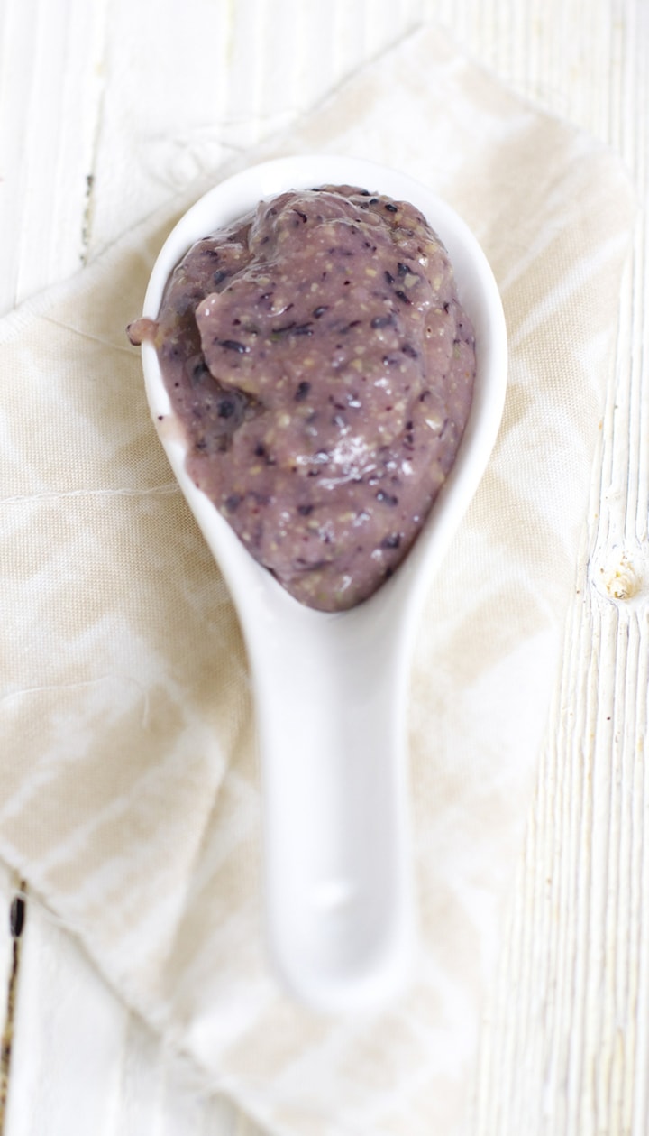Spoon resting on napkin full of blueberry chickpea baby food puree.
