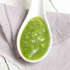 Spoon with a green chicken baby food puree inside.