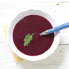 Small white bowl filled with bright purple baby food puree.