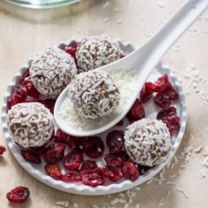 Four cranberry snowballs in a bowl and one on a spoon.