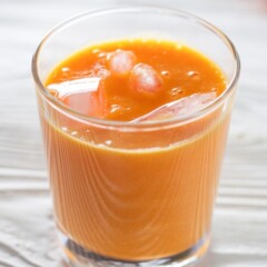 glass of carrot and orange juice with ice.