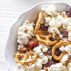 A bowl of popcorn with trail mix inside.