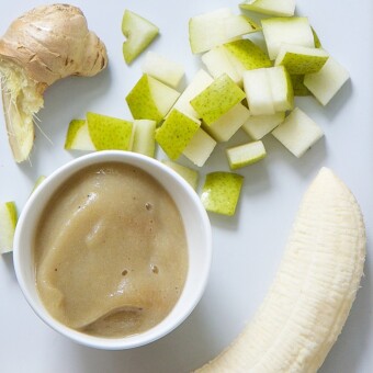 A bowl of banana and pear puree surrounded by bananas, pears, and fresh ginger.