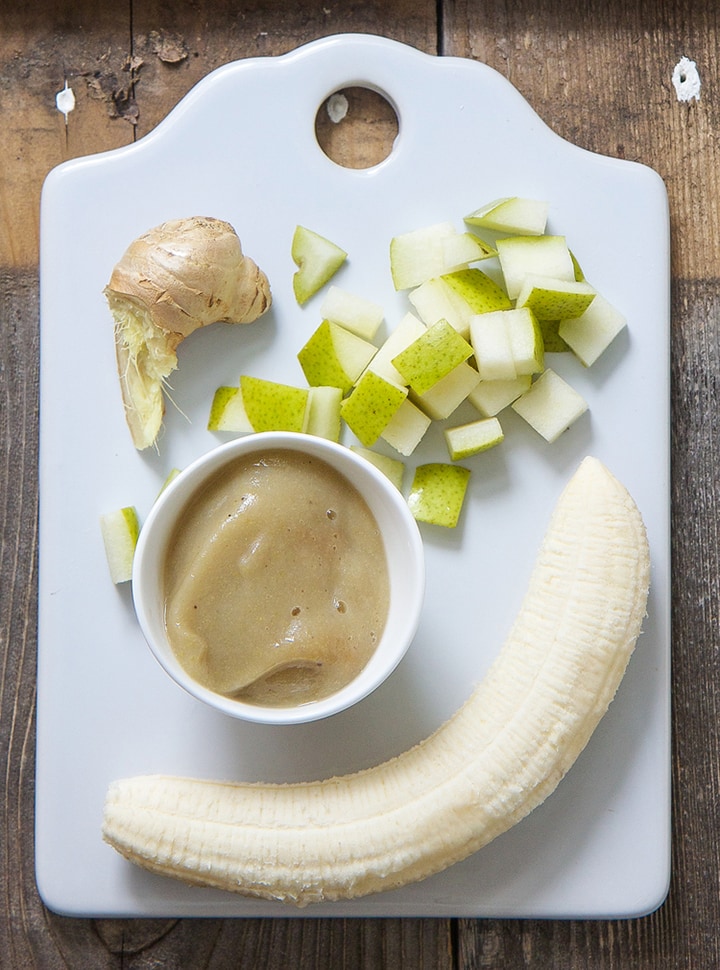 Spread of banana, chopped pear, ginger and a small bowl of baby food puree. 