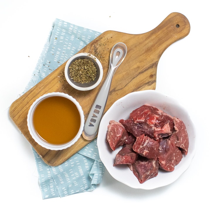 Spread of ingredients needed for this recipe - beef, dried herbs and broth. 