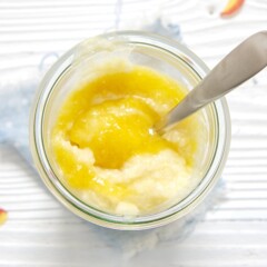 Clear glass jar filled with peach rice pudding for baby and toddler.