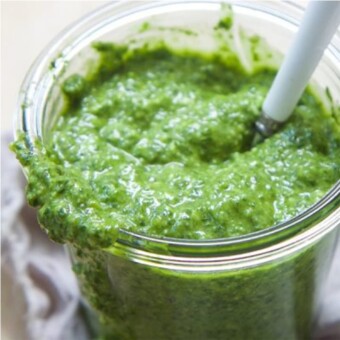 lemon basil pesto in a glass jar with a spoon.