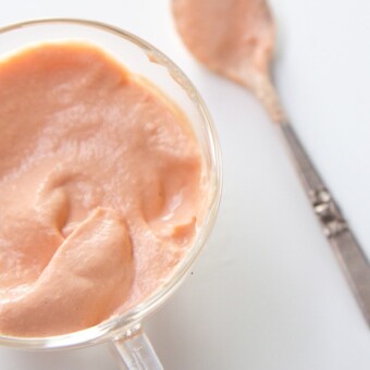 Salmon baby food puree in a small glass cup with a baby spoon.