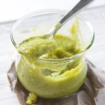 Broccoli asparagus green baby food combination puree in a small glass with a spoon.