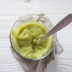 A clear glass jar filled with a smooth green baby food puree.
