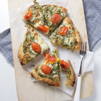 Spinach and artichoke pizza on a cutting board.