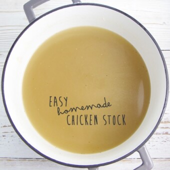 white saucepan with grey rim on a white wooden background filled with an easy homemade chicken stock