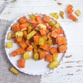 Diced roasted root vegetables for toddlers and baby led weaning on a small white plate.