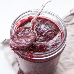 Cherry almond chia jam on a spoon and in a glass jar.