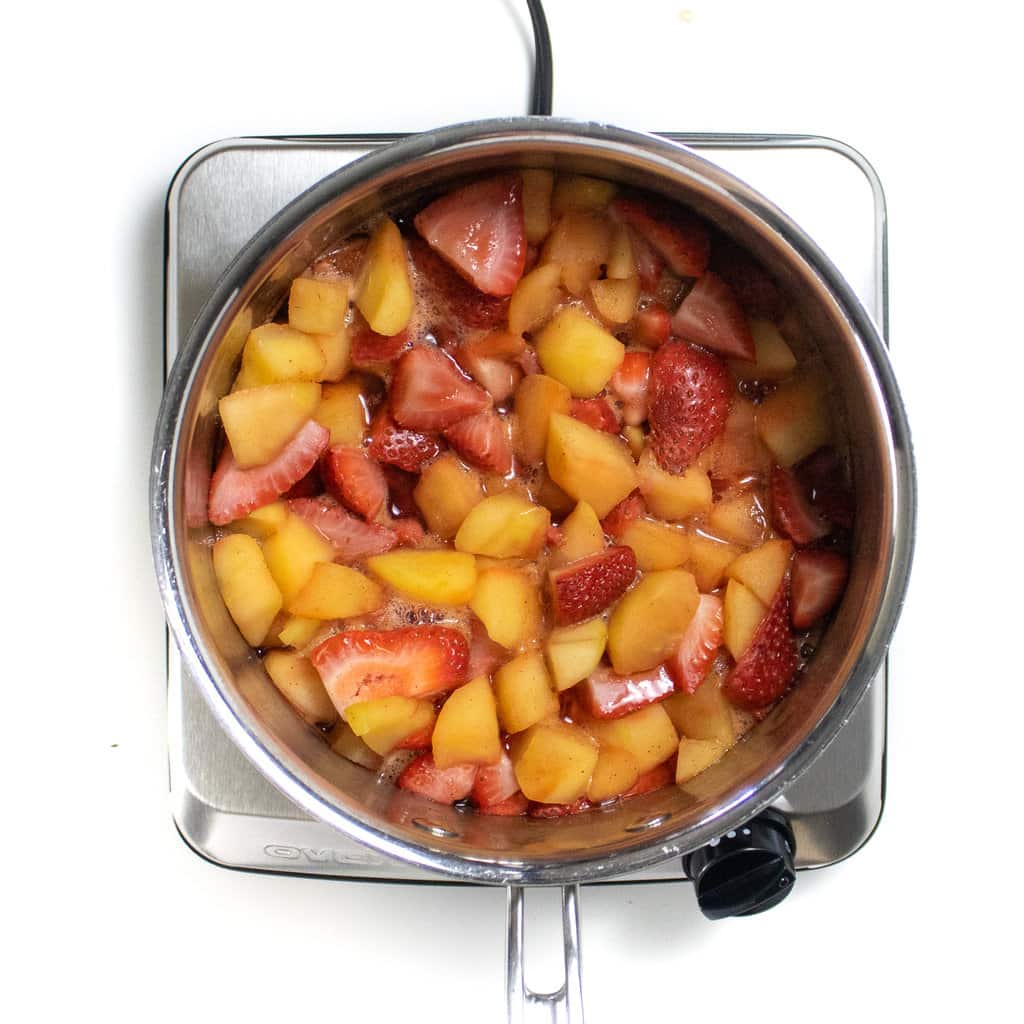 a silver saucepan Pan with smart apples strawberries, cinnamon and vanilla.