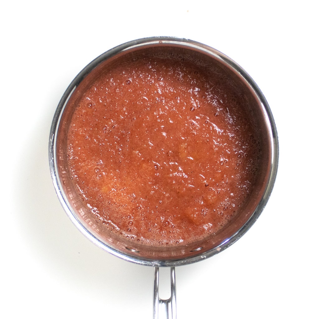 A silver saucepan with blended strawberry applesauce.
