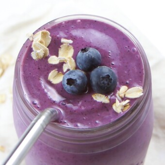 Blueberry pie smoothie in a mason jar garnished with oats and fresh blueberries.