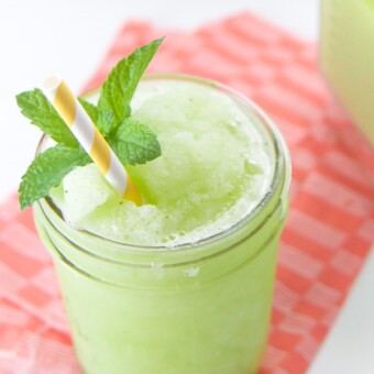 Sugar free mint and lime slushy in a glass cup with a yellow straw.