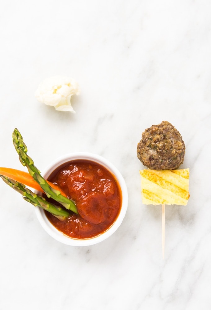 Grilled polenta and meatball skewer with tomato sauce on marble counter