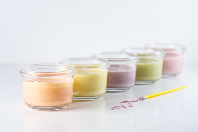 Clear jars of colorful finger paints lined up in a row.