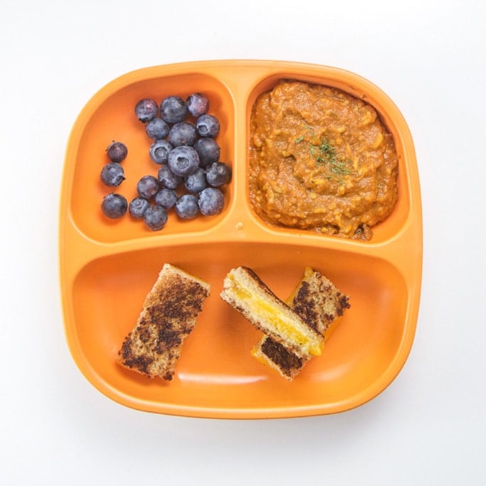 A nutritious lunch for toddlers on a sectioned orange plate.