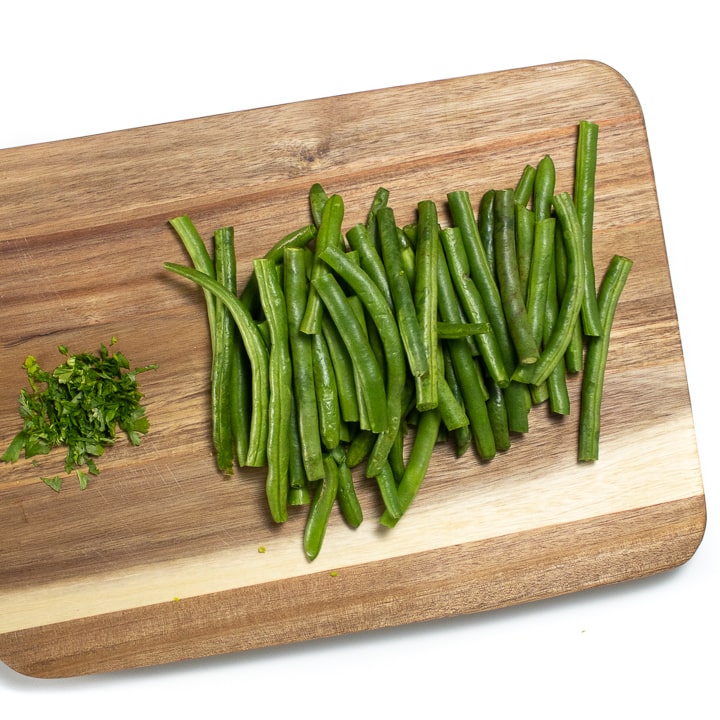Green beans and cilantro on a cutting board.