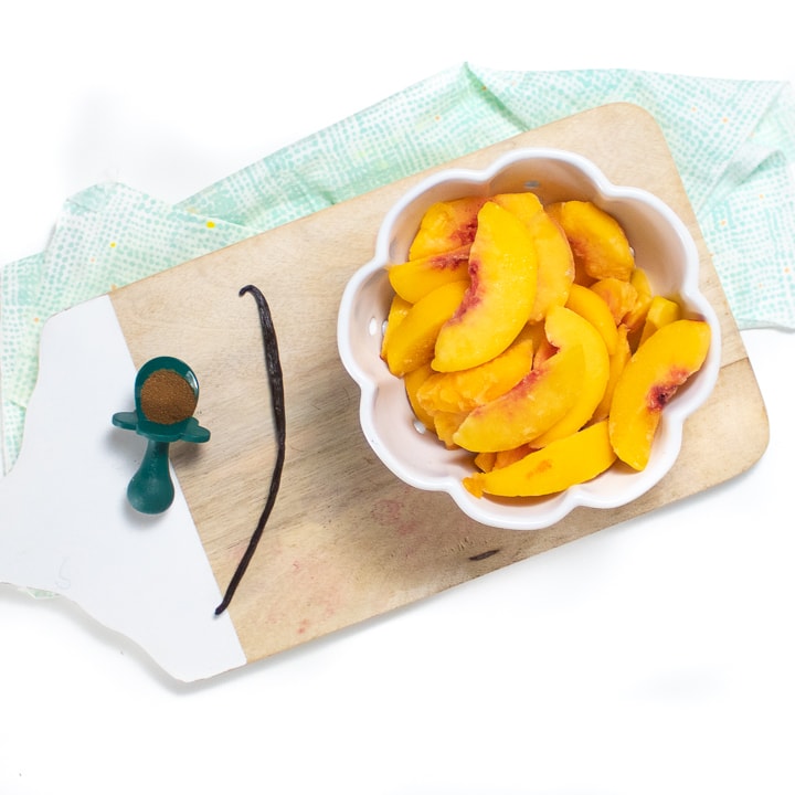 Cutting board with peaches, vanilla bean and cloves.