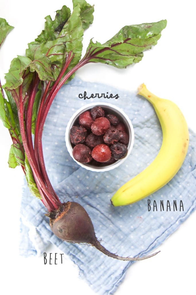 Layout of beets, cherries, bananas on top of a blue napkin. 
