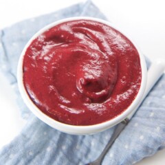 A small white bowl filled with a bright red baby food puree.