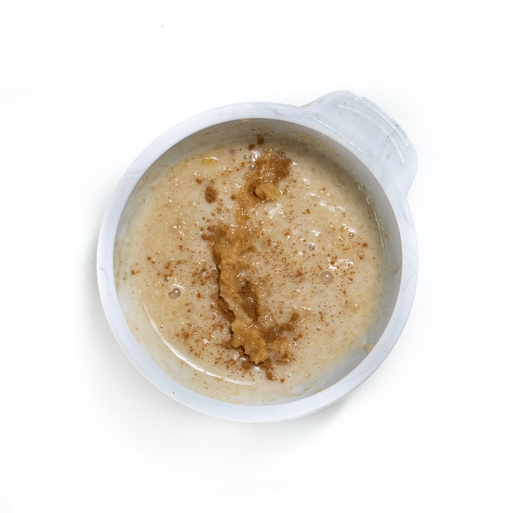 Small gray baby bowl filled with oatmeal with peanut butter and cinnamon.
