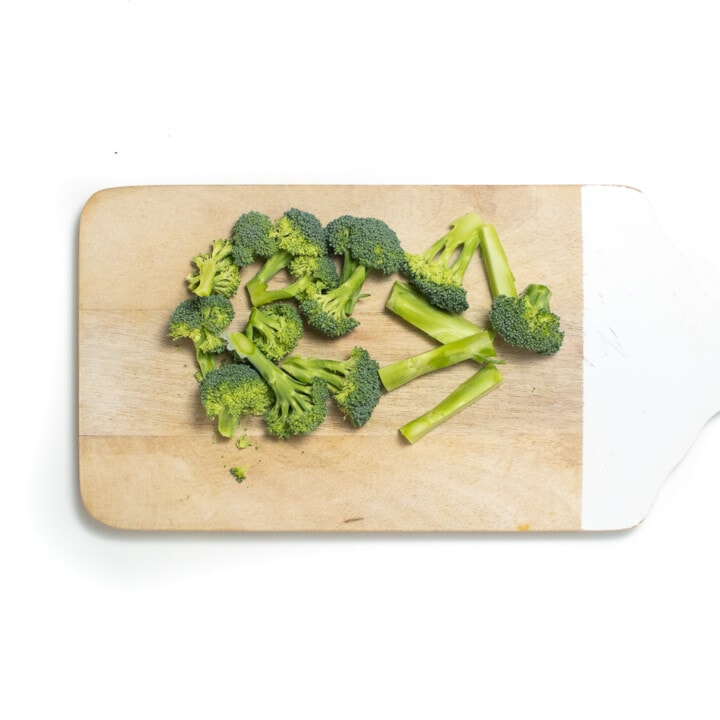 Cutting board with chopped broccoli.
