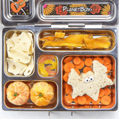 Image is of an open lunch box with healthy halloween themed food inside.