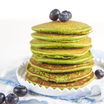 A stack of healthy gluten free blender spinach pancakes topped with fresh blueberries.