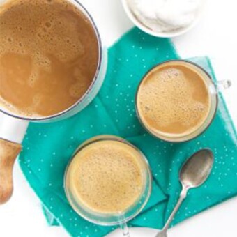 Two mugs of turmeric cocoa on a blue cloth.