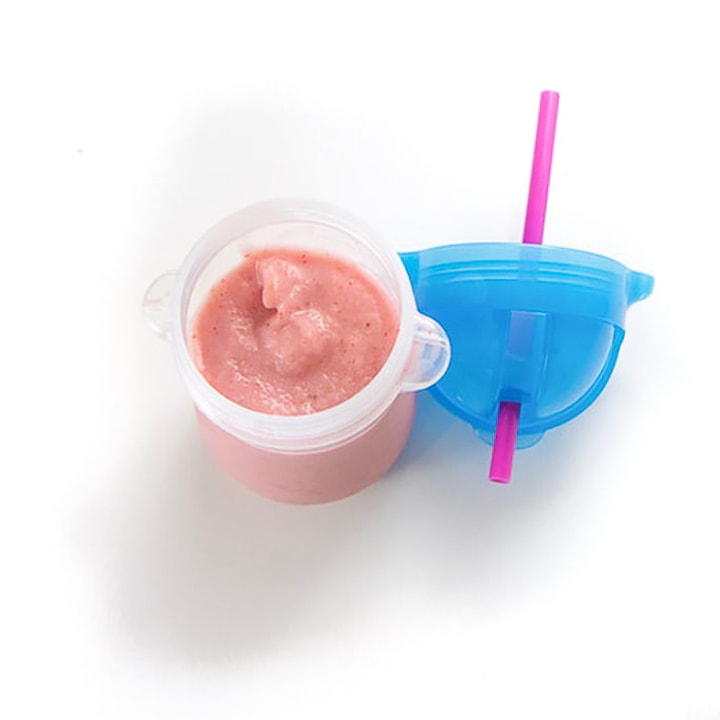 Baby cup with blue lid with strawberry banana smoothie inside.