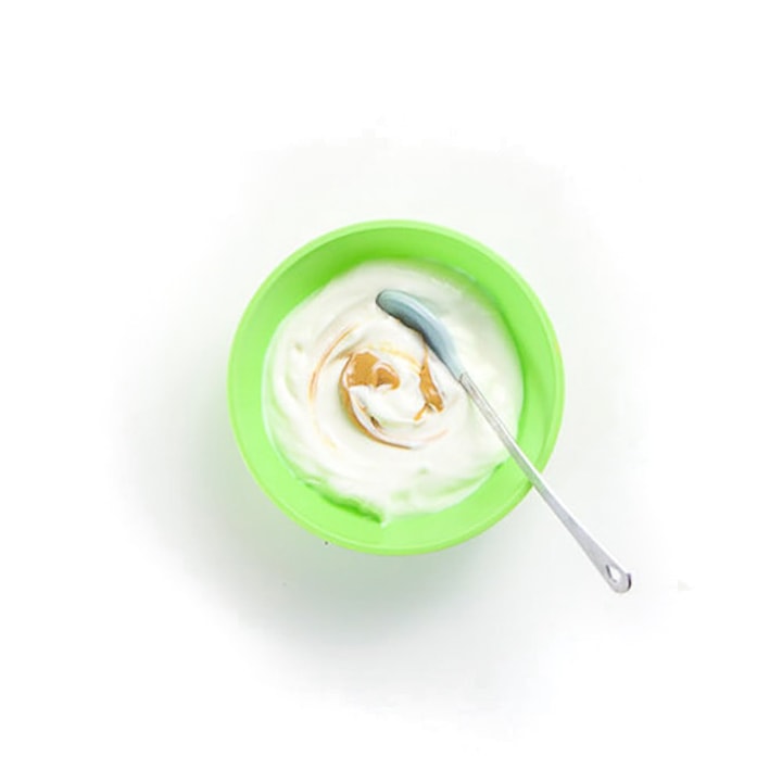 Green baby bowl with yogurt and swirl of peanut butter.