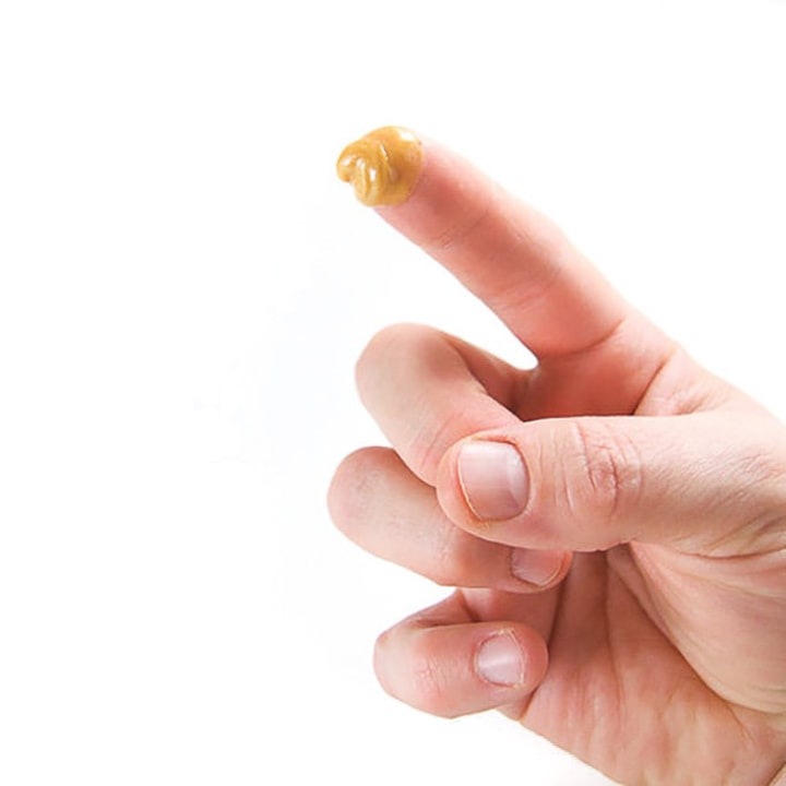 Finger with dollop of nut butter on the tip.