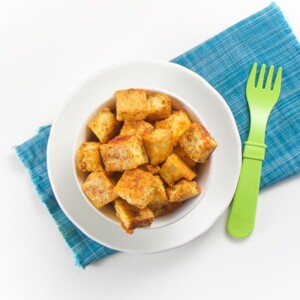 baby-led weaning nuggets - small white bowl on top of blue napkin that is filled with seasoned tofu chunks