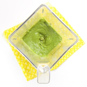baby puree recipe - a blender is sitting on top a yellow napkin. Inside blender is a smooth green puree