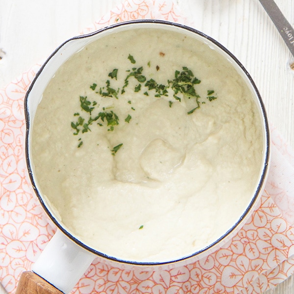 Small white saucepan with chicken puree inside with a sprinkle of parsley on top. 