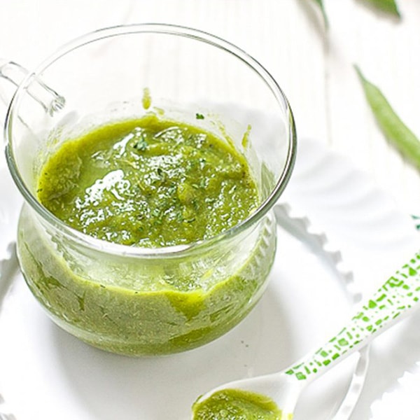 A clear jar is filled with a homemade green bean puree with parsley - great for 4 months and up