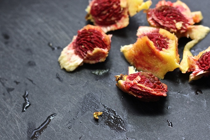 Pits of the peaches sitting on a black cutting board. 
