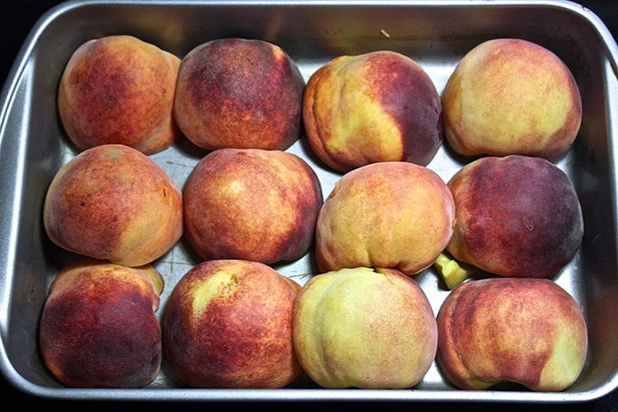 peaches cut in half and lined up in a baking dish. 