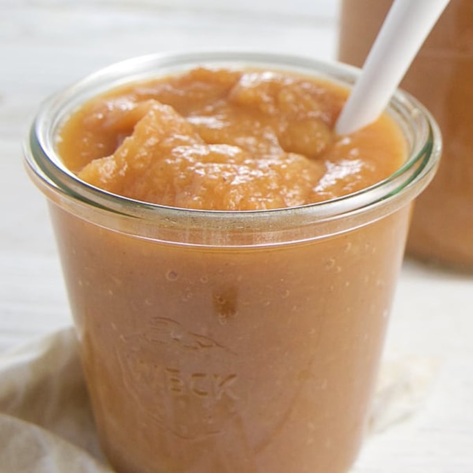 A clear jar filled with carrot applesauce. 