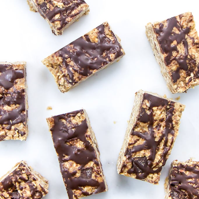 Chewy chocolate granola bars are scattered around a white surface.